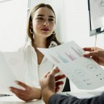 Two people holding papers with graphs and charts